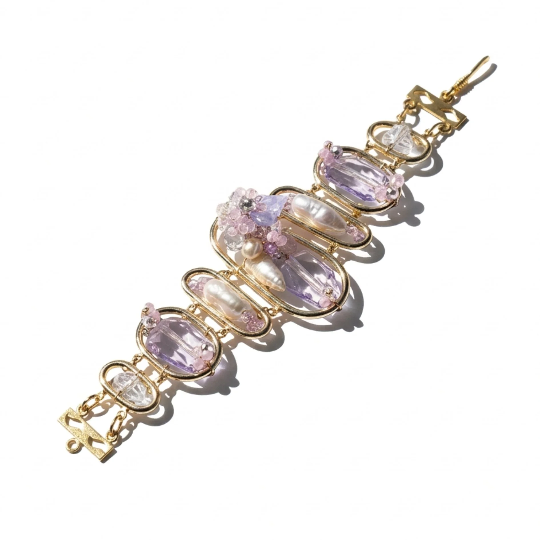 Gold bracelet with pale amethyst gemstones, baroque pearls, pastel crystal clusters, and sculptural open links on a white background.