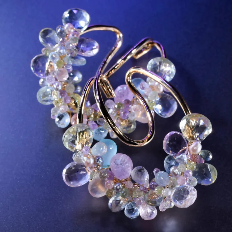 The Pastel Gemstone Ear Cuffs: looping gold wire edged with clusters of pale pink, lilac and clear briolettes, on a blue backdrop