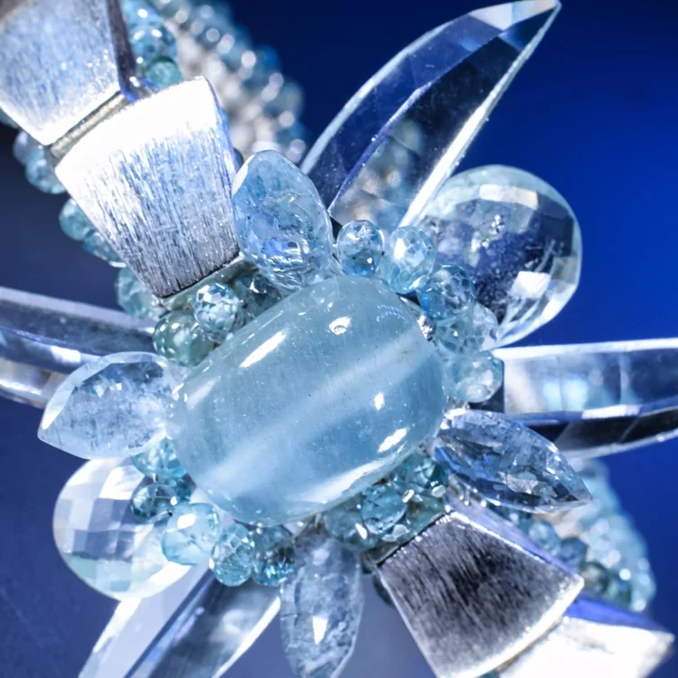 A close-up of an aqua stone in a burst of clear crystal points and silver spikes