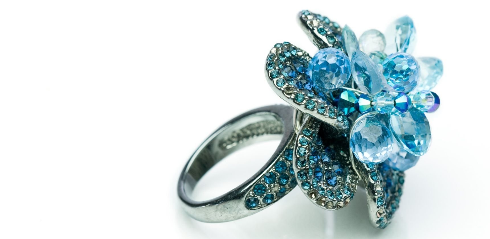 Close view of an Andrea Li statement cocktail ring: a cluster of faceted aqua and blue gemstones on a pave-set band