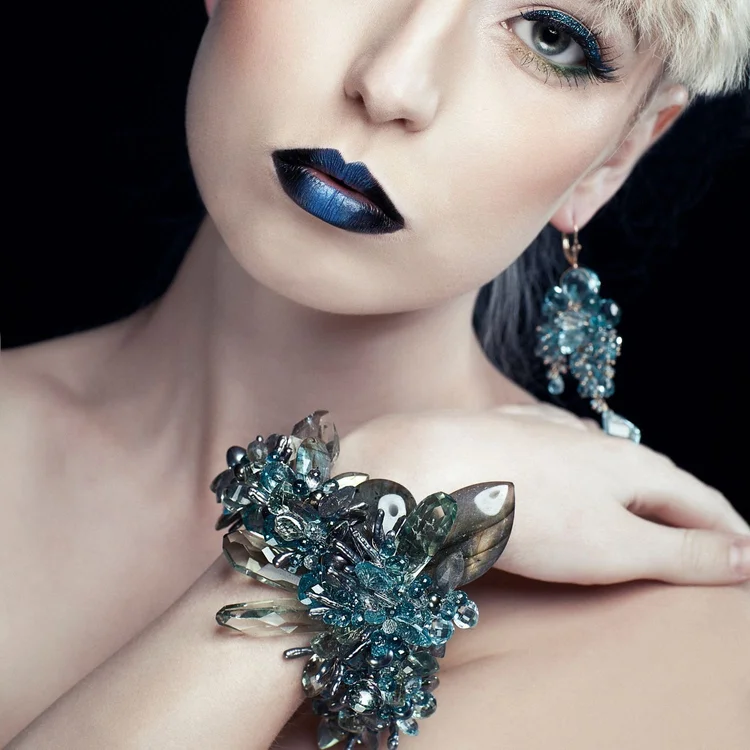 A platinum-haired model with blue lips wearing an Andrea Li blue gemstone statement cuff, by Andrea Li