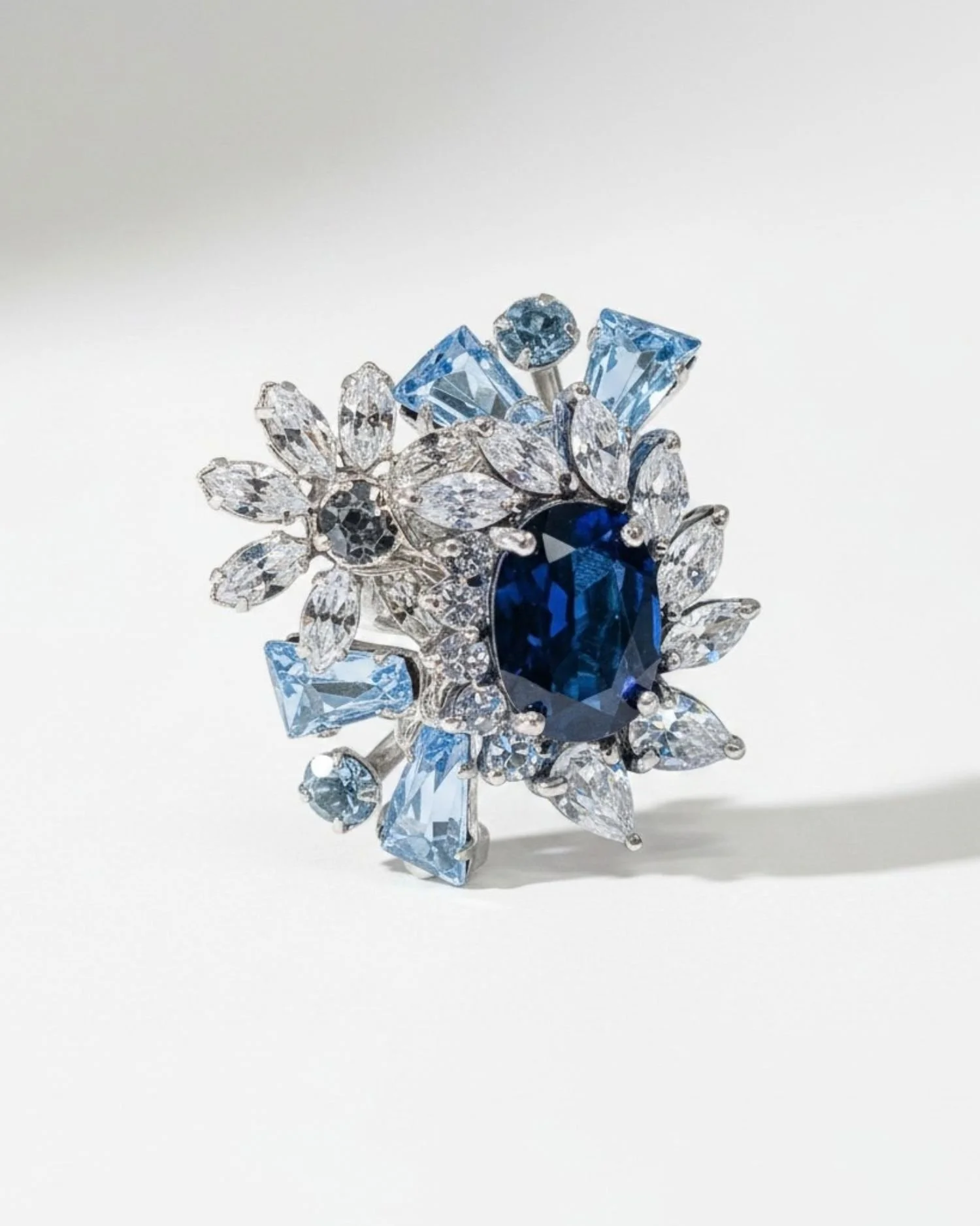 A custom Andrea Li cocktail ring: a deep blue oval center stone in a burst of aqua and clear gemstones
