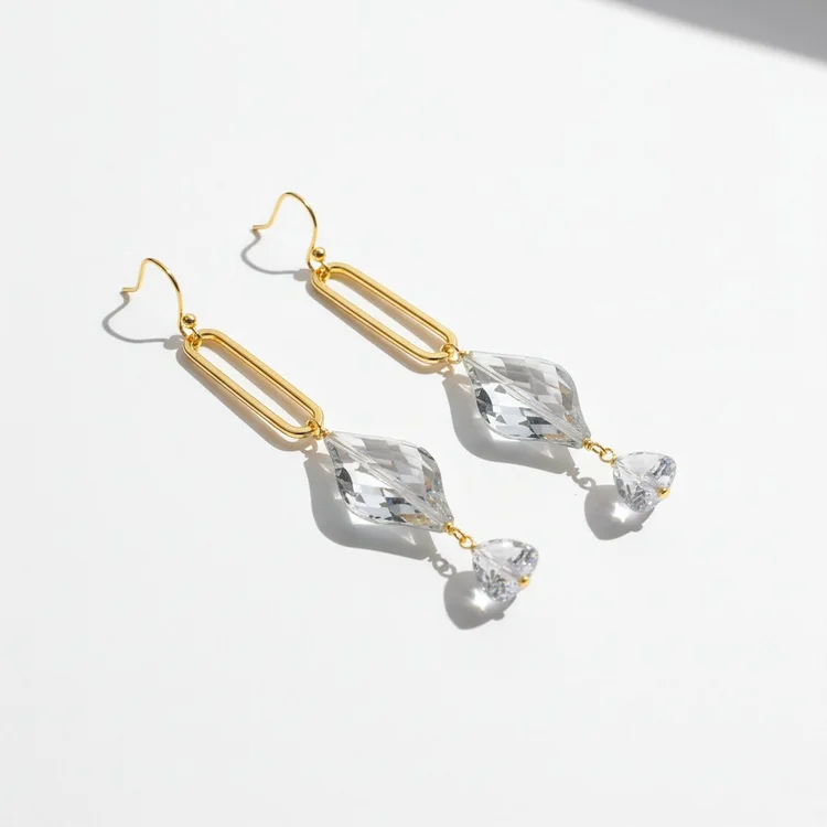 Pair of long gold drop earrings featuring open rectangular links, large clear faceted crystals, and small dangling clear stones, photographed on a white background with soft shadows.