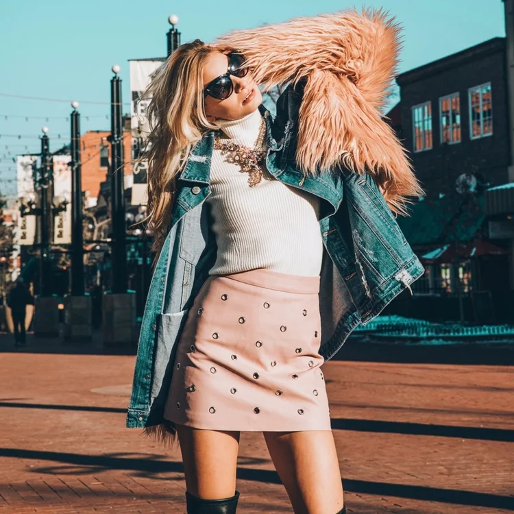 Model in sunglasses, a pink fur-trimmed denim jacket and a pink skirt, wearing a vintage statement necklace