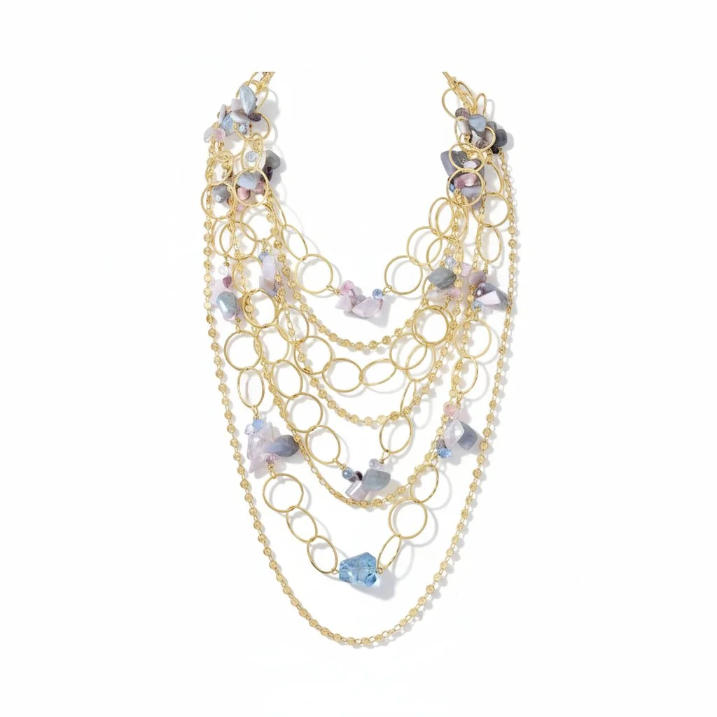 Layered gold necklace with oversized open-circle links and cascading chains accented with pastel gemstone chips (lavender, pink, gray) and a faceted blue stone drop.