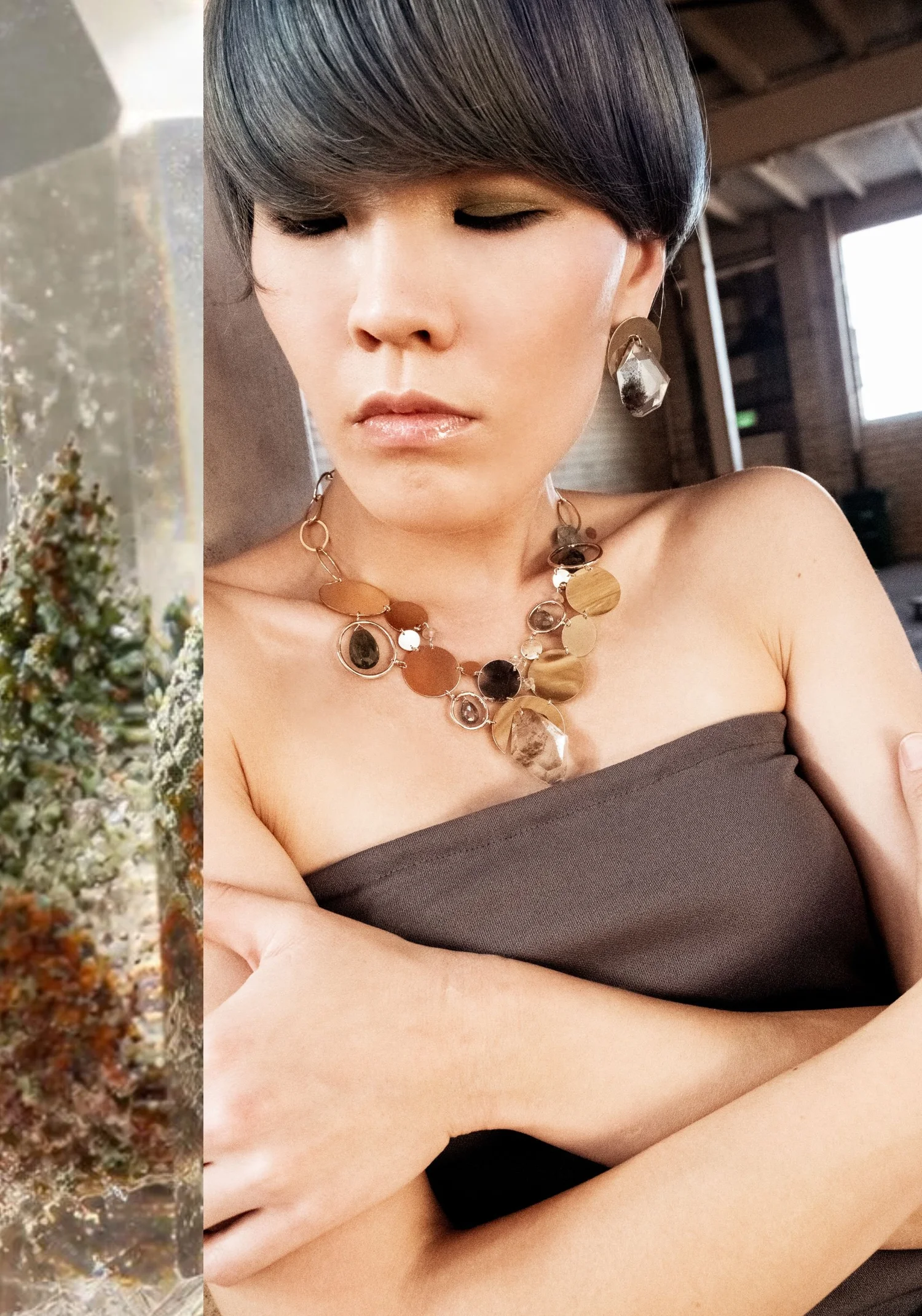 A model in a strapless taupe top wearing a gold multi-disk statement necklace and drop earrings set with clear included quartz, beside a close-up of garden quartz inclusions that look like moss and rust-colored trees
