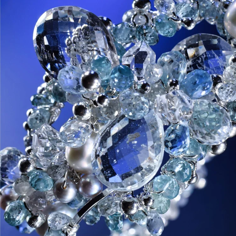 Macro of an Andrea Li bracelet encrusted with faceted aquamarine and clear gemstones on deep blue, by Andrea Li