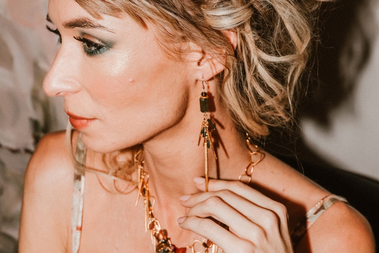 A model in profile wearing a long Andrea Li tourmaline earring with gold accents, by Andrea Li