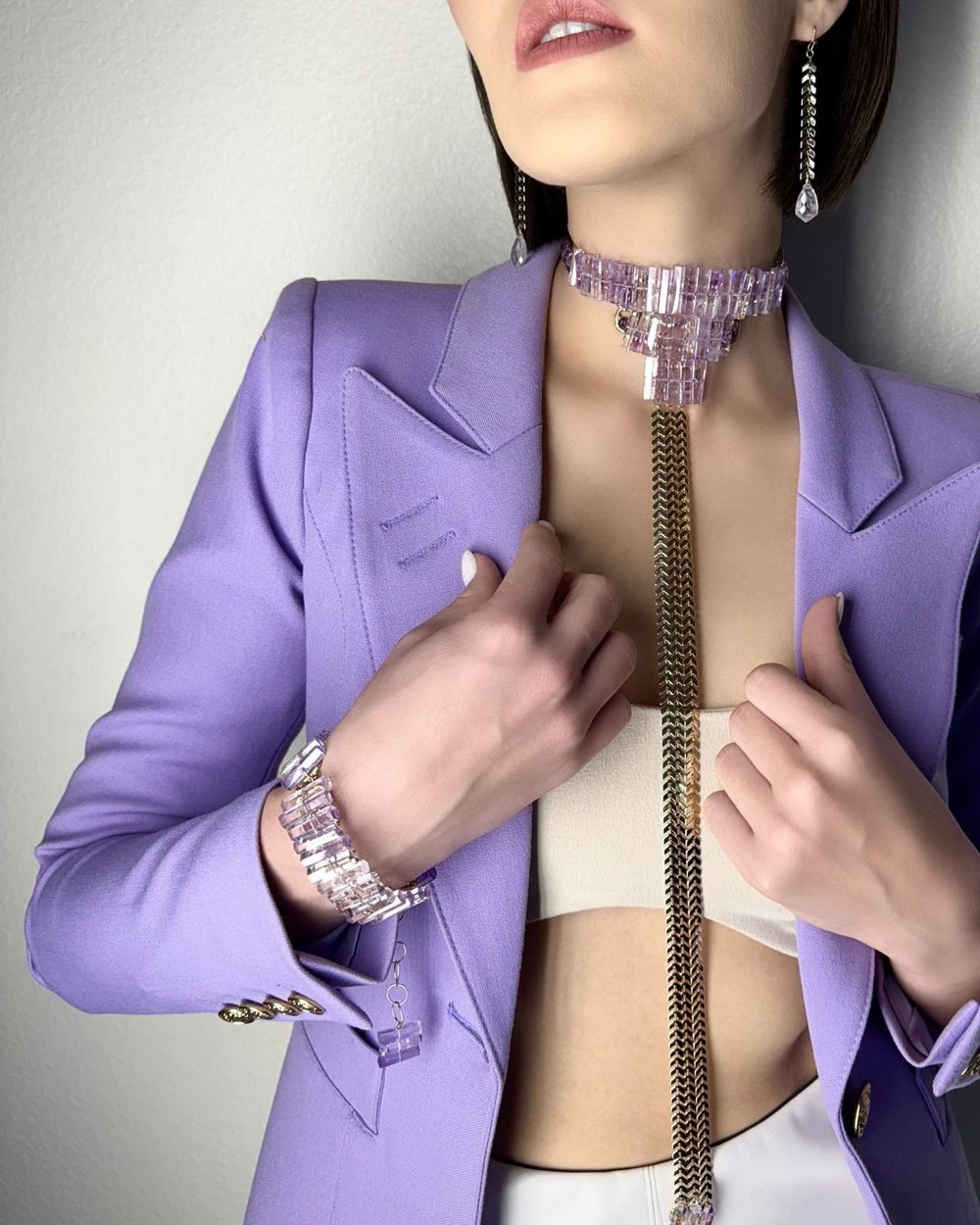 A model in a lavender blazer wearing an Andrea Li pastel gemstone bracelet and a long gemstone choker, by Andrea Li