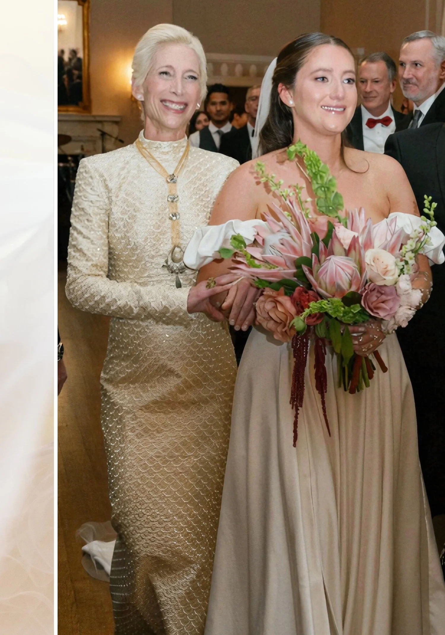 A mother with white hair in an ivory and gold brocade coat and a long pendant necklace walking the bride, in a champagne gown with a pink protea bouquet, down the aisle