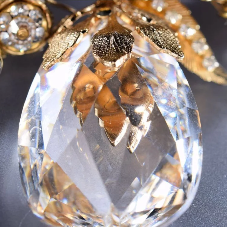 Close-up of a large faceted clear crystal drop beneath vintage gold leaf components