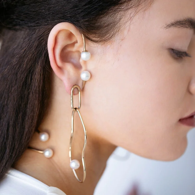 Close view of an ear with an Andrea Li pearl ear climber and a long gold link earring with pearls, by Andrea Li