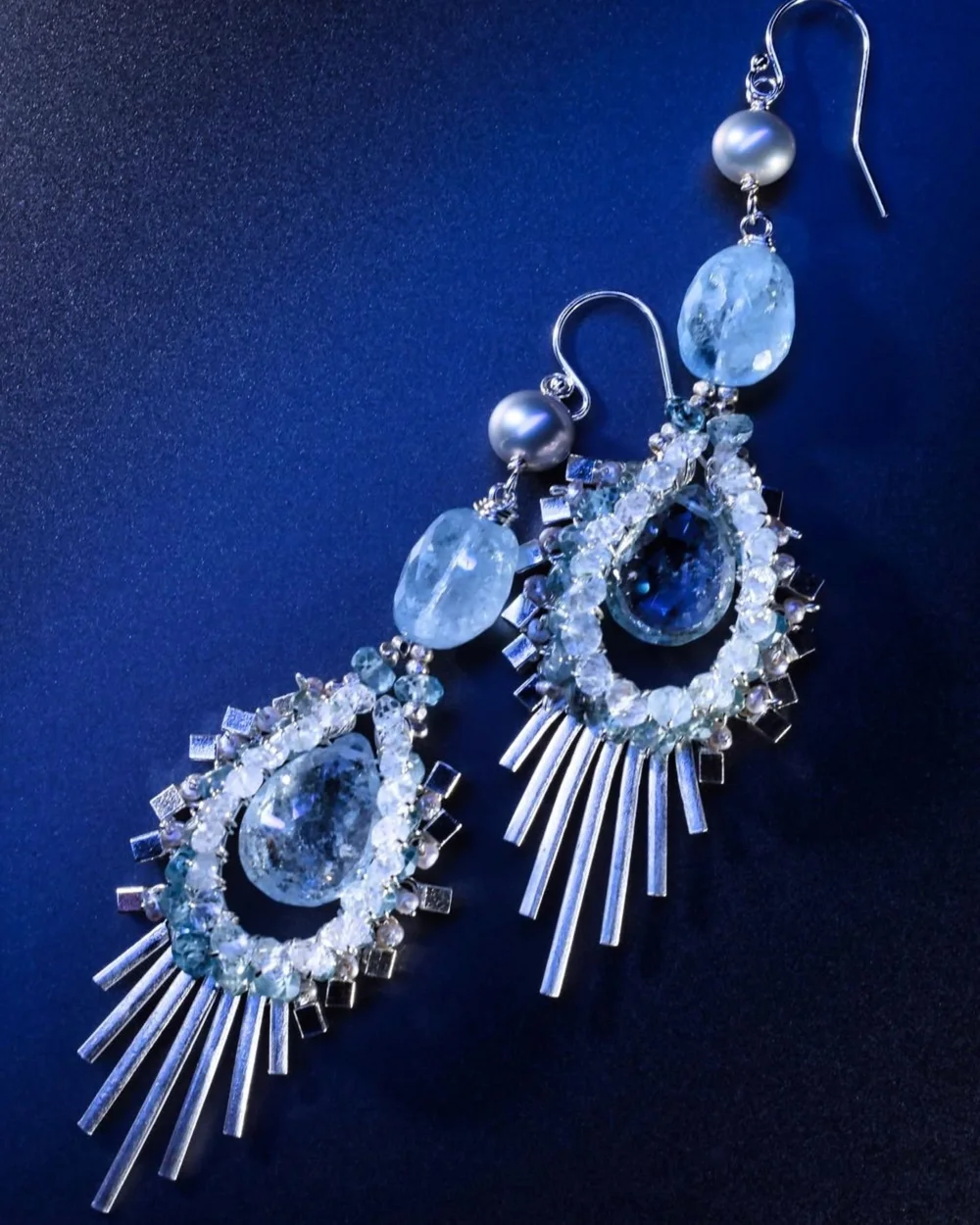 Andrea Li silver teardrop earrings with pale blue gemstones and a fringe of silver spikes on deep blue, by Andrea Li