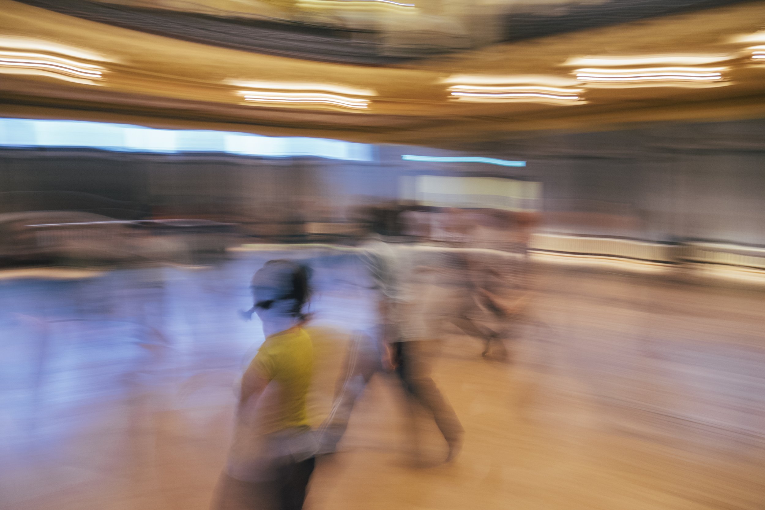  extra blurred mage of people in a wooden floored room walking and running together 