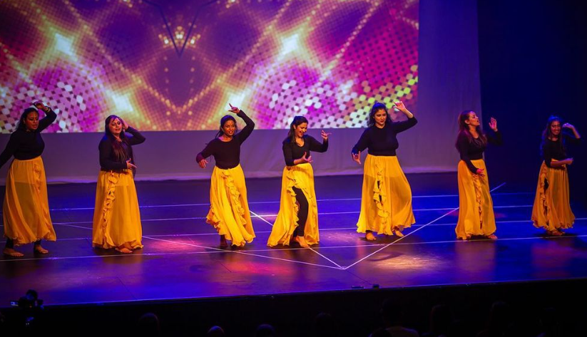  Seven women dancing onstage in costumes 