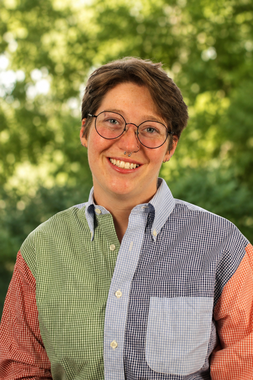 person with short brown hair and glasses smiling