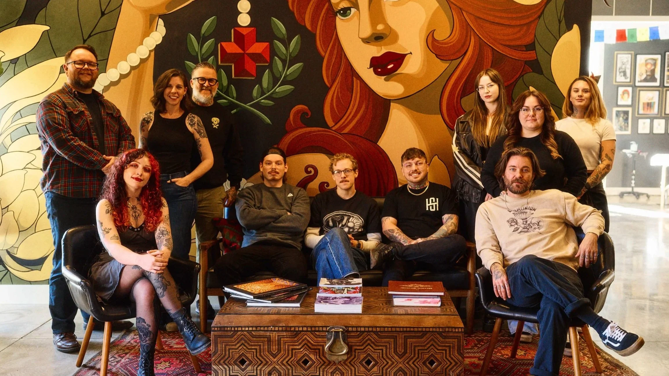 Tattoo artists at Safe House Tattoo Studio in Nashville, TN posing together inside the studio with mural artwork
