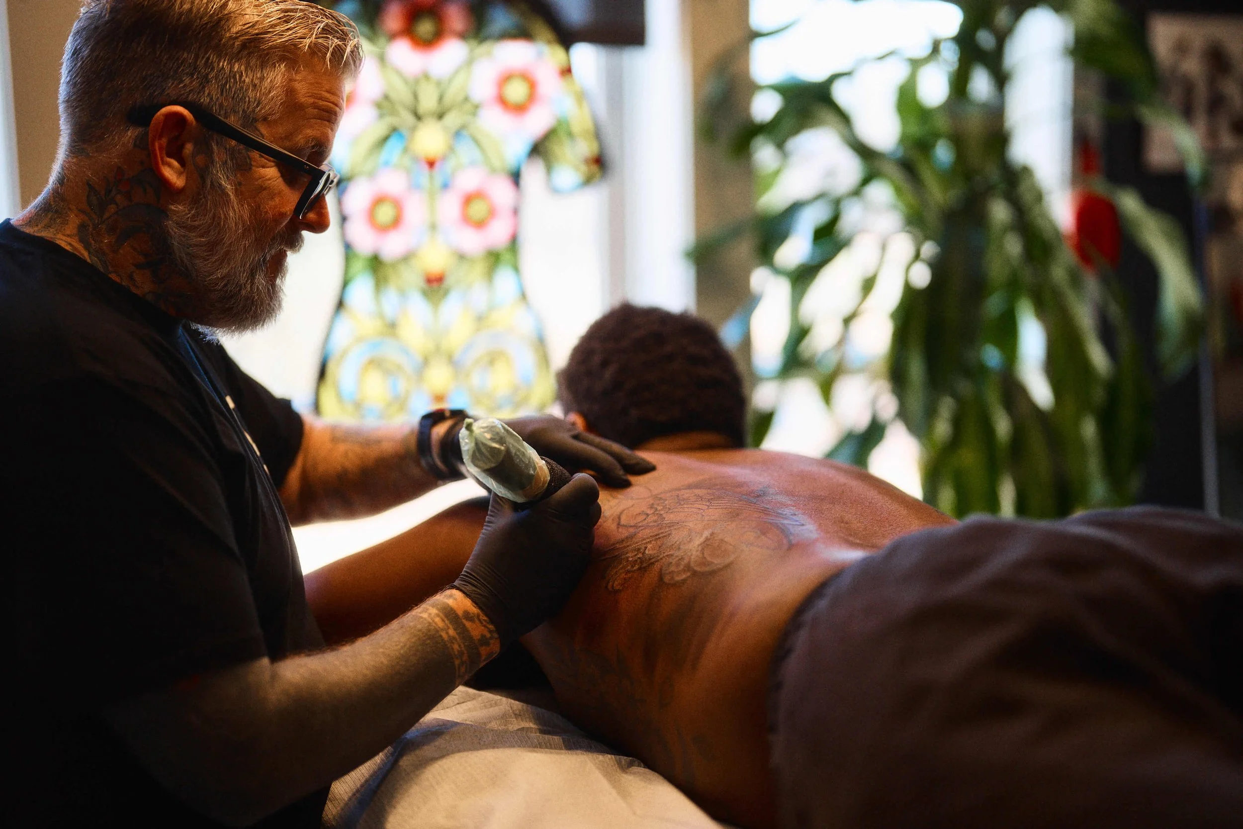 Tattoo artist working on a client’s back at Safe House Tattoo Studio in Nashville, Tennessee