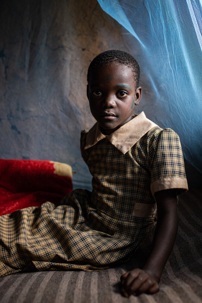  Eight-year-old Trizah Makungu sits on the bed she shares with her parents, protected by a mosquito net. These nets, which cost about $5 on the local market, have helped save millions of lives. 
