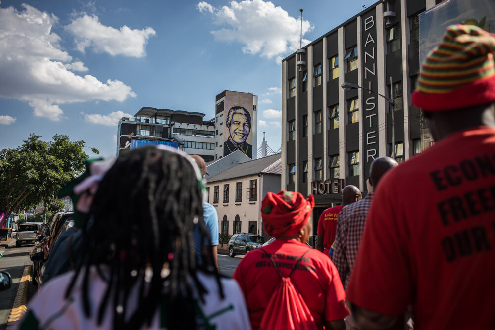 EFF activists during a demonstration in Braamfontein, Johannesburg. In the back the Purple Shall Govern Mandela Graffiti. 