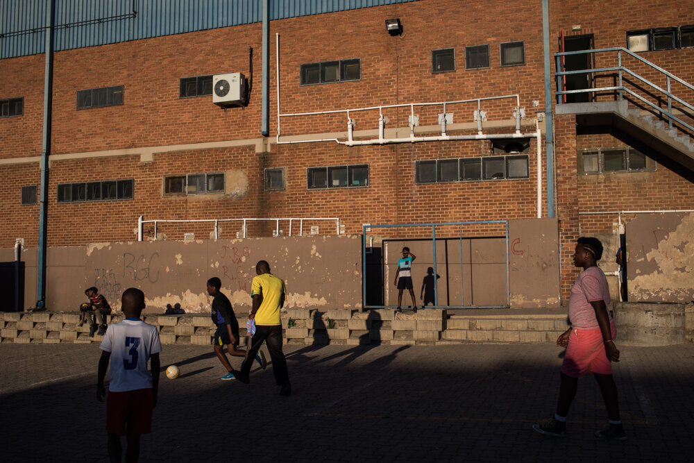  Katlego plays football with children in front of the football stadium in Alexandra. The stadium once was public and everybody could use it. Now groups have to pay in order to use it. “This is one reason why I am fighting, I want this to be a better 