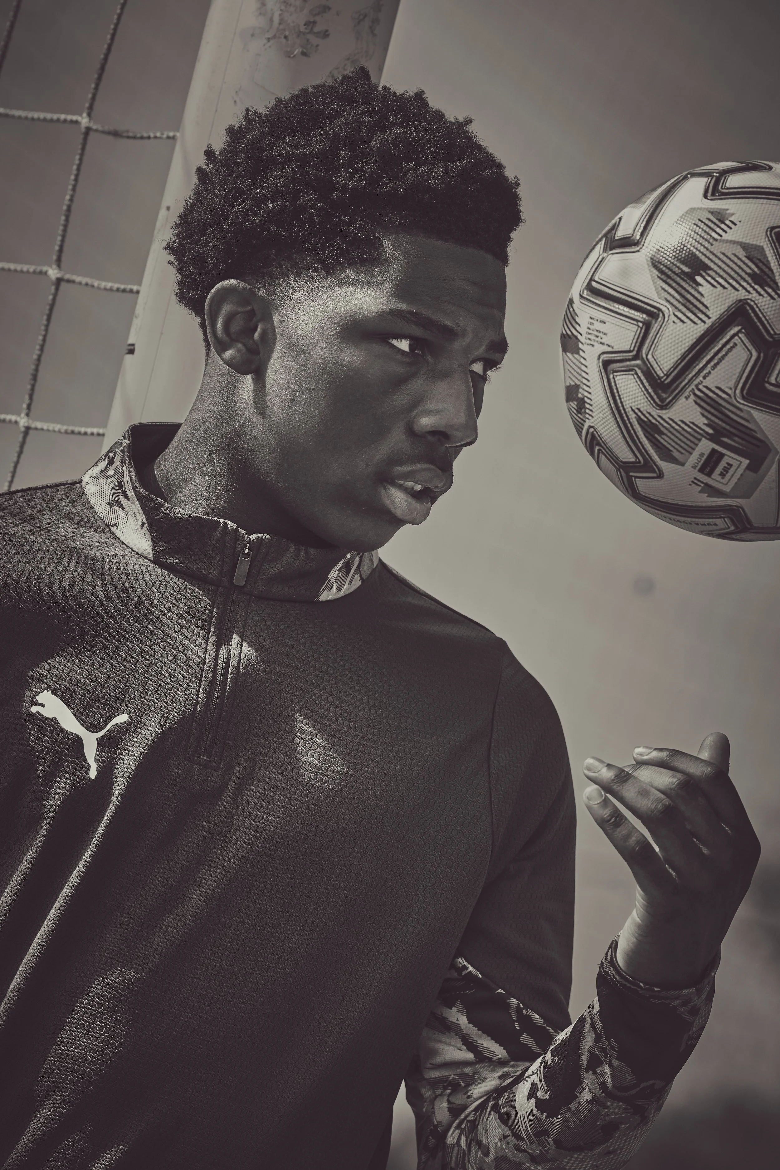 A young man in sportswear is holding a soccer ball close to his face.