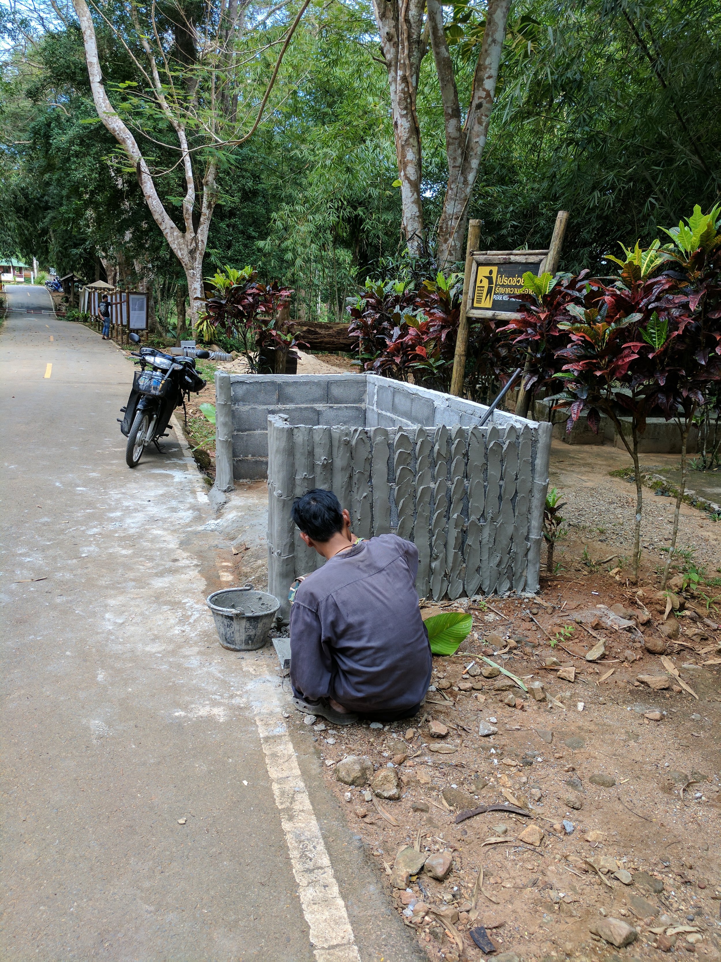 In a national park in Phuket, I passed a worker creating a cement fence around some trash cans. 