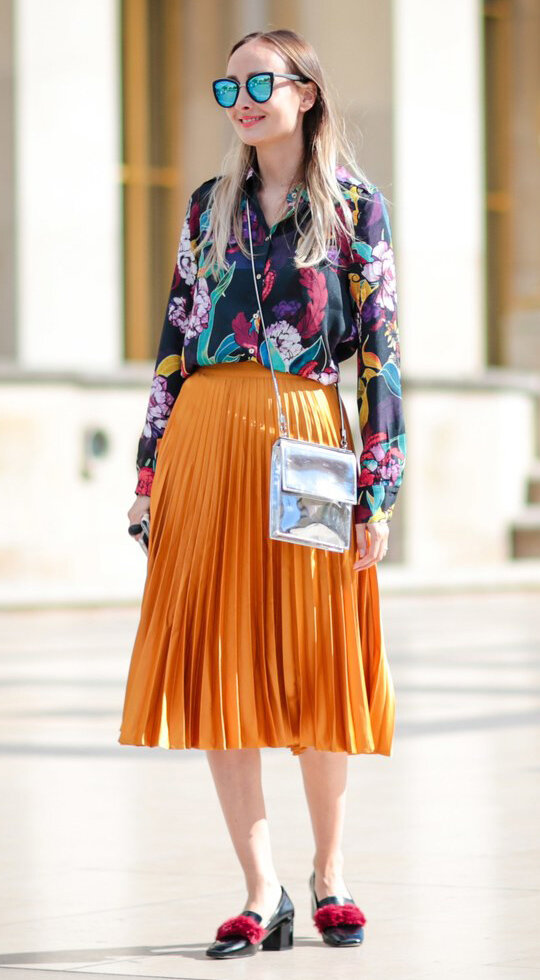 orange-midi-skirt-pleated-black-top-blouse-print-sun-blonde-gray-bag-silver-metallic-black-shoe-pumps-summer-work.jpg