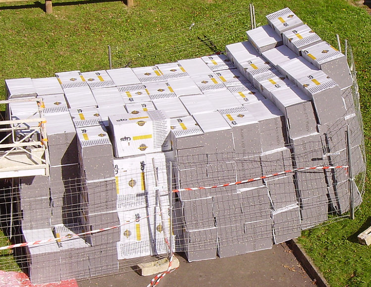 Large stacks of polystyrene insulation blocks stored outdoors at a construction site