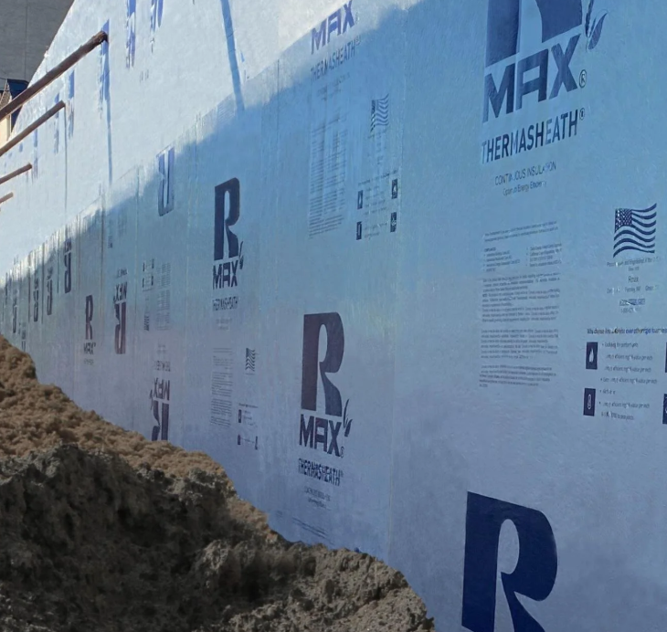 Exterior wall with rigid insulation panels installed along a below-grade foundation.