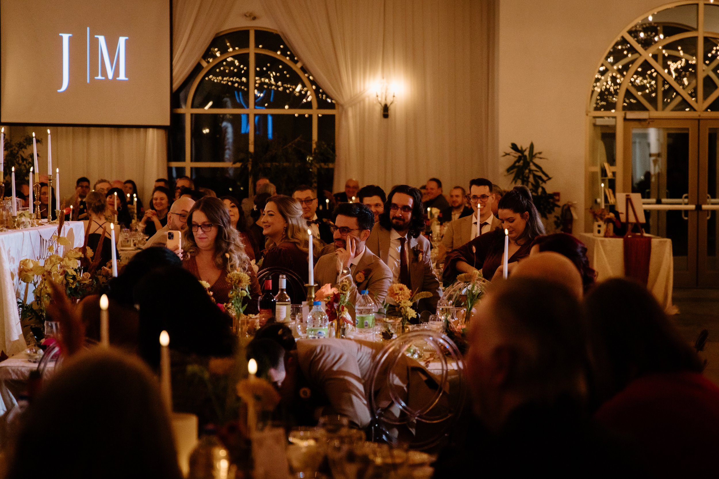 Candid room photo of guests attentively listening to a speech during dinner at a Caledon wedding reception