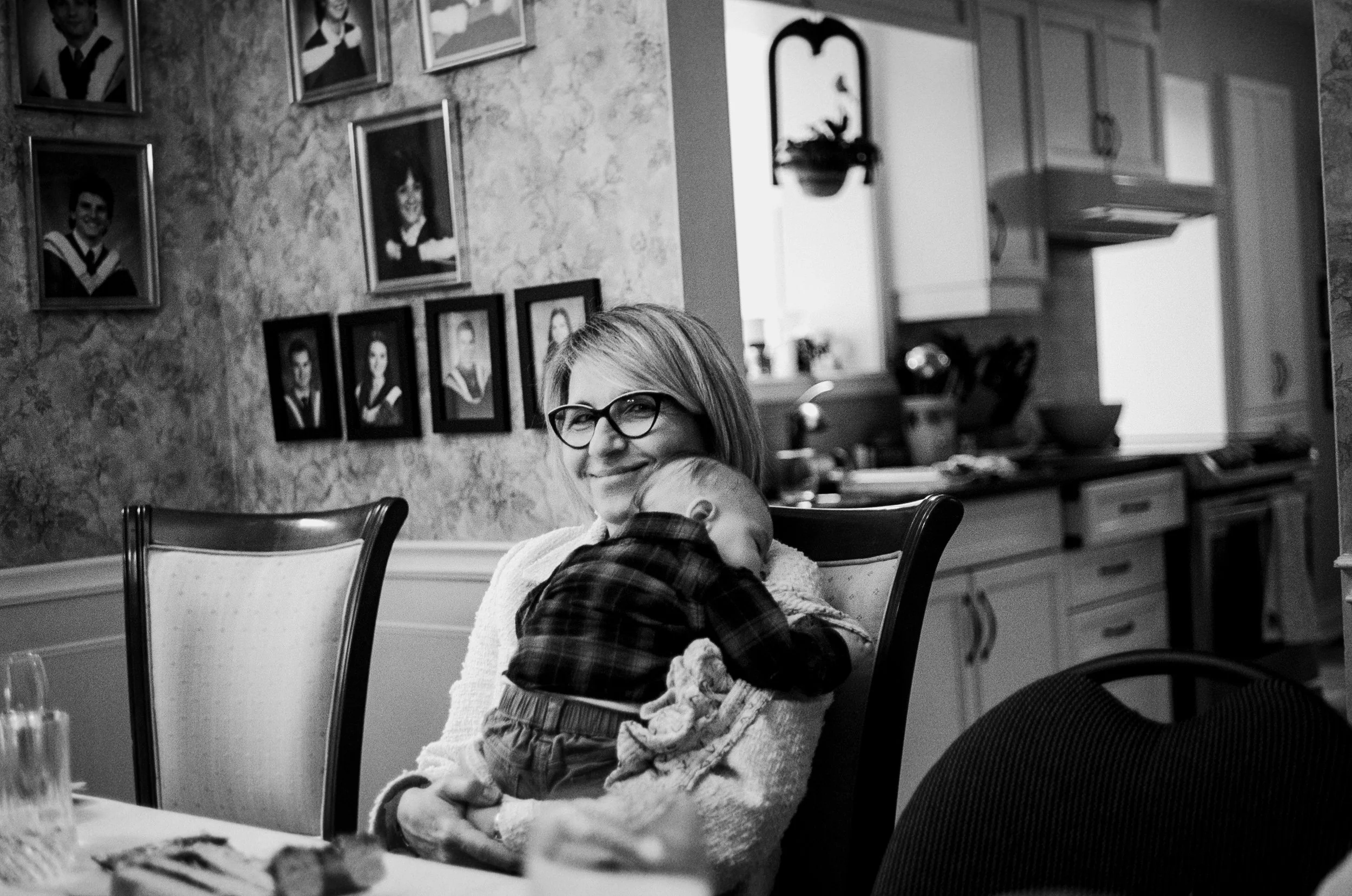 Candid film photograph of a wedding guest holding a sleeping baby during an intimate at-home wedding dinner in Toronto
