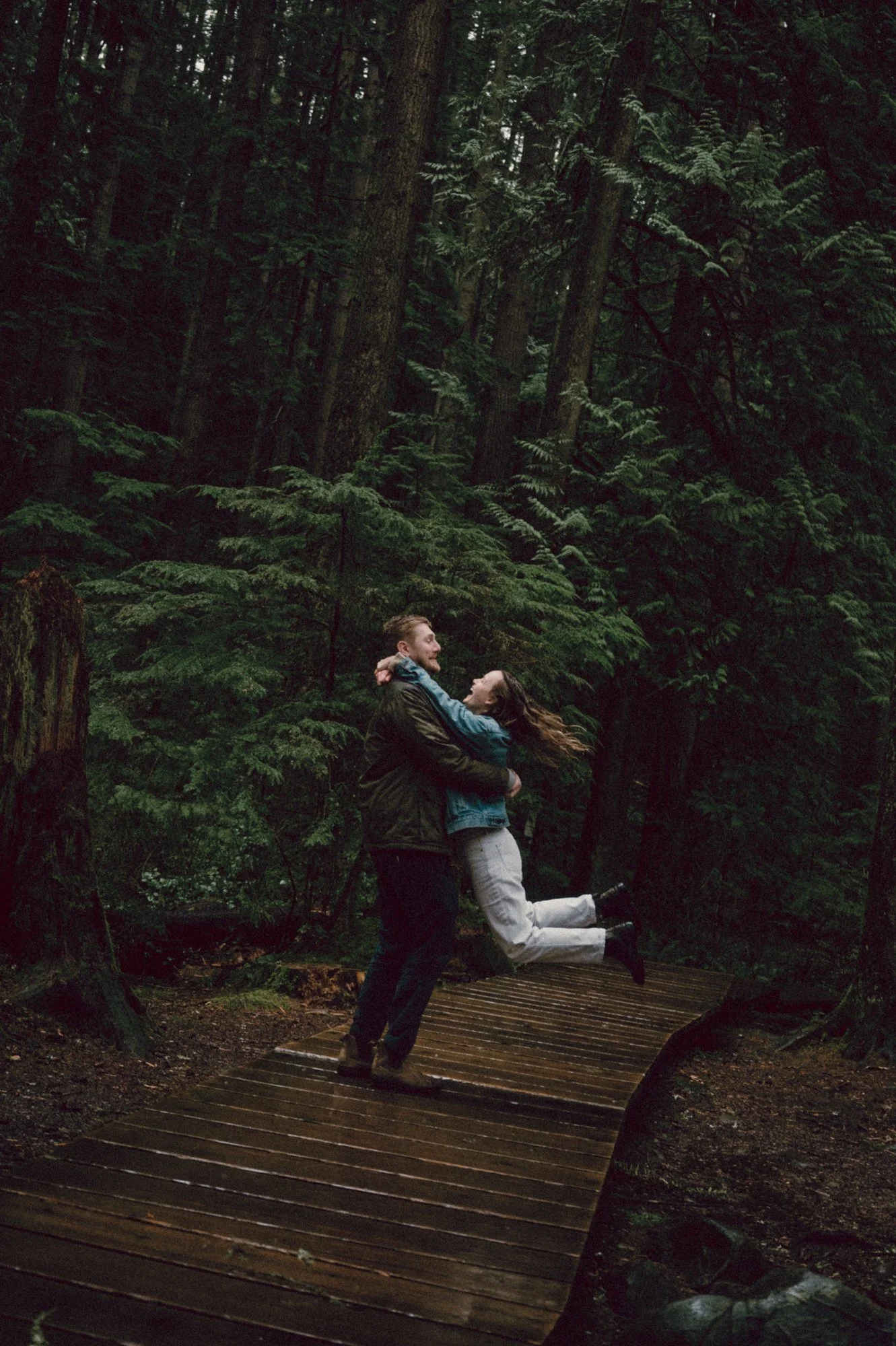 Candid photo of a couple playfully spinning around during their engagement session in Lynn Valley, North Vancouver