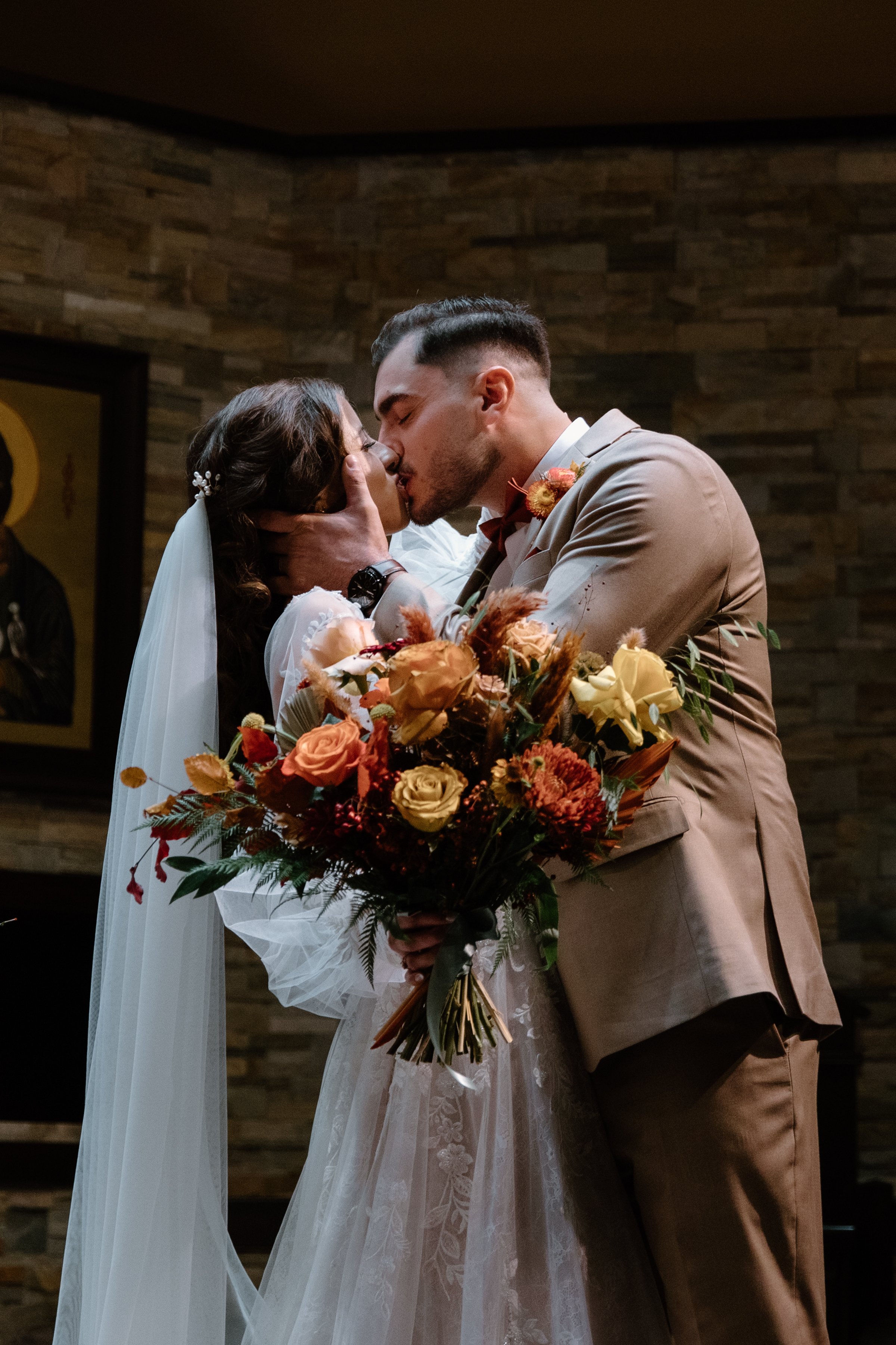 Romantic photo of a bride and groom sharing their first kiss during their church wedding ceremony in Toronto