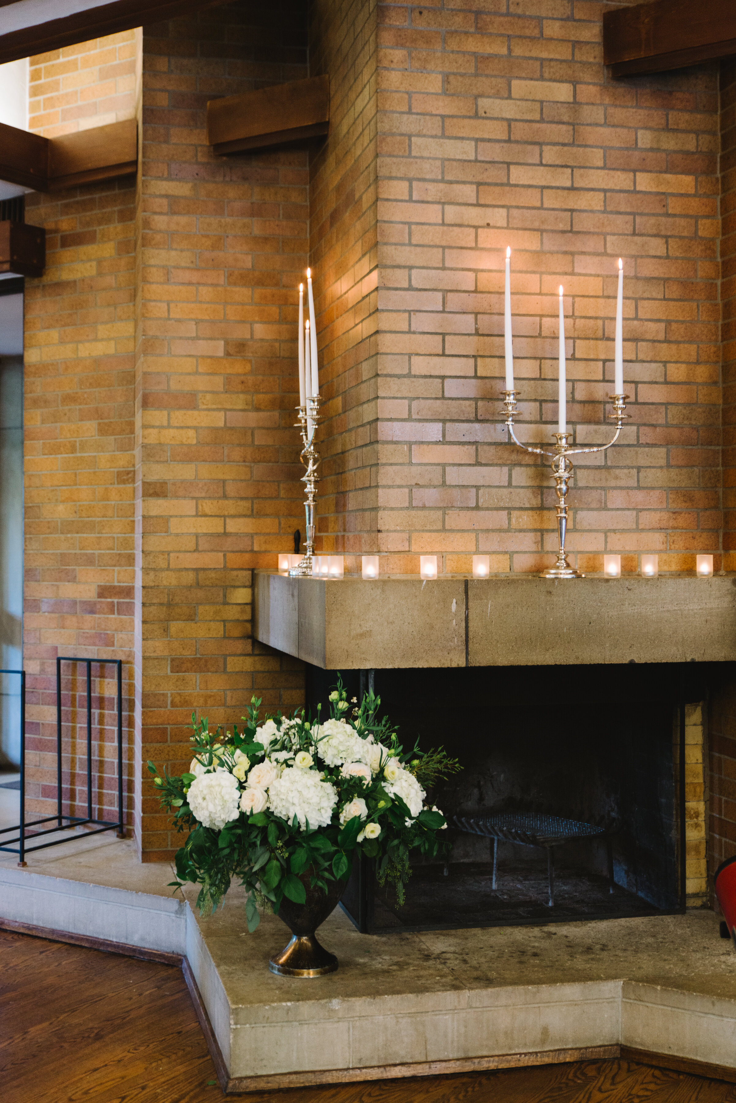 Fireplace with candles and floral arrangement at Massey College wedding reception