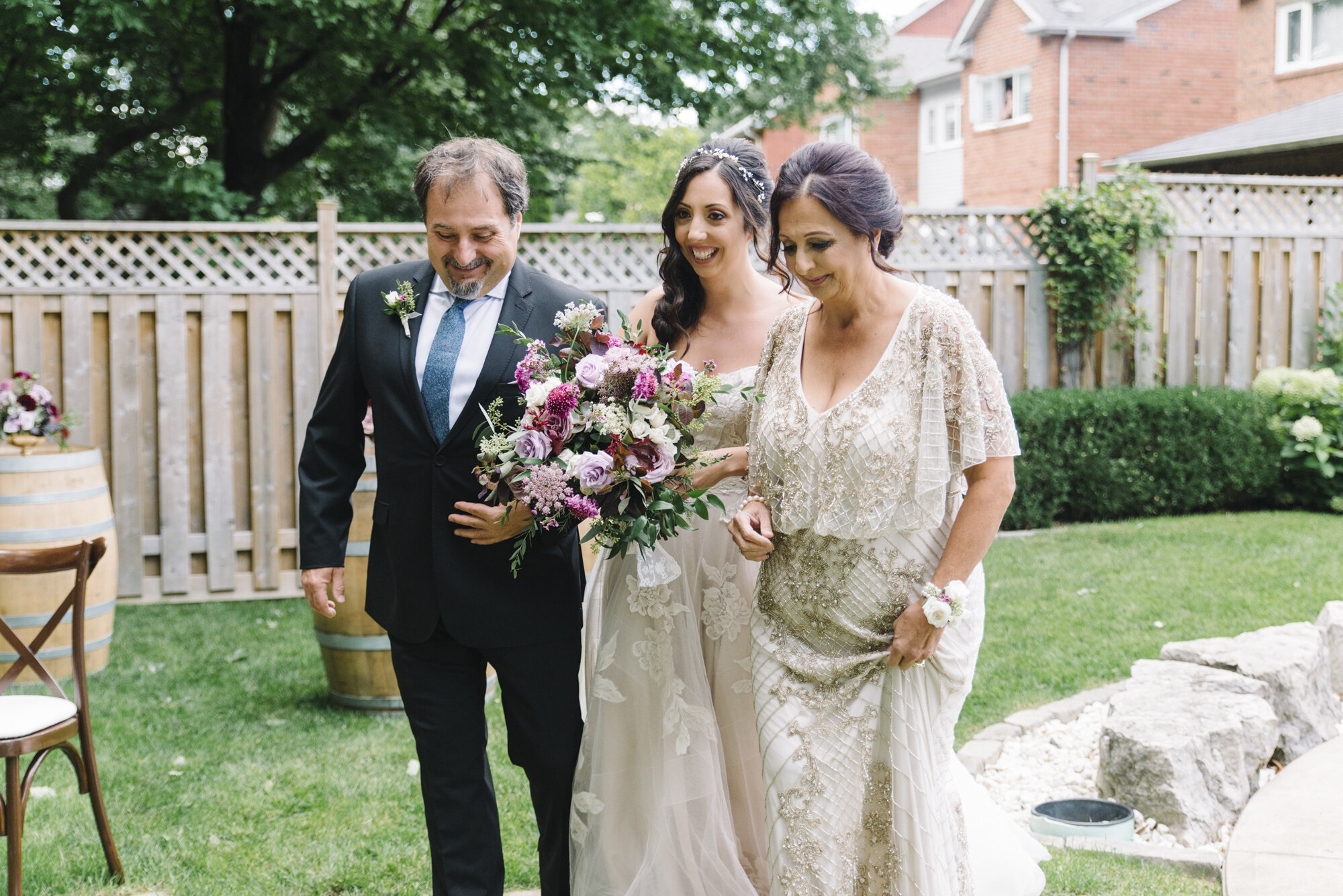 Candid photo of a bride walking with her parents to the ceremony at a backyard elopement in Toronto