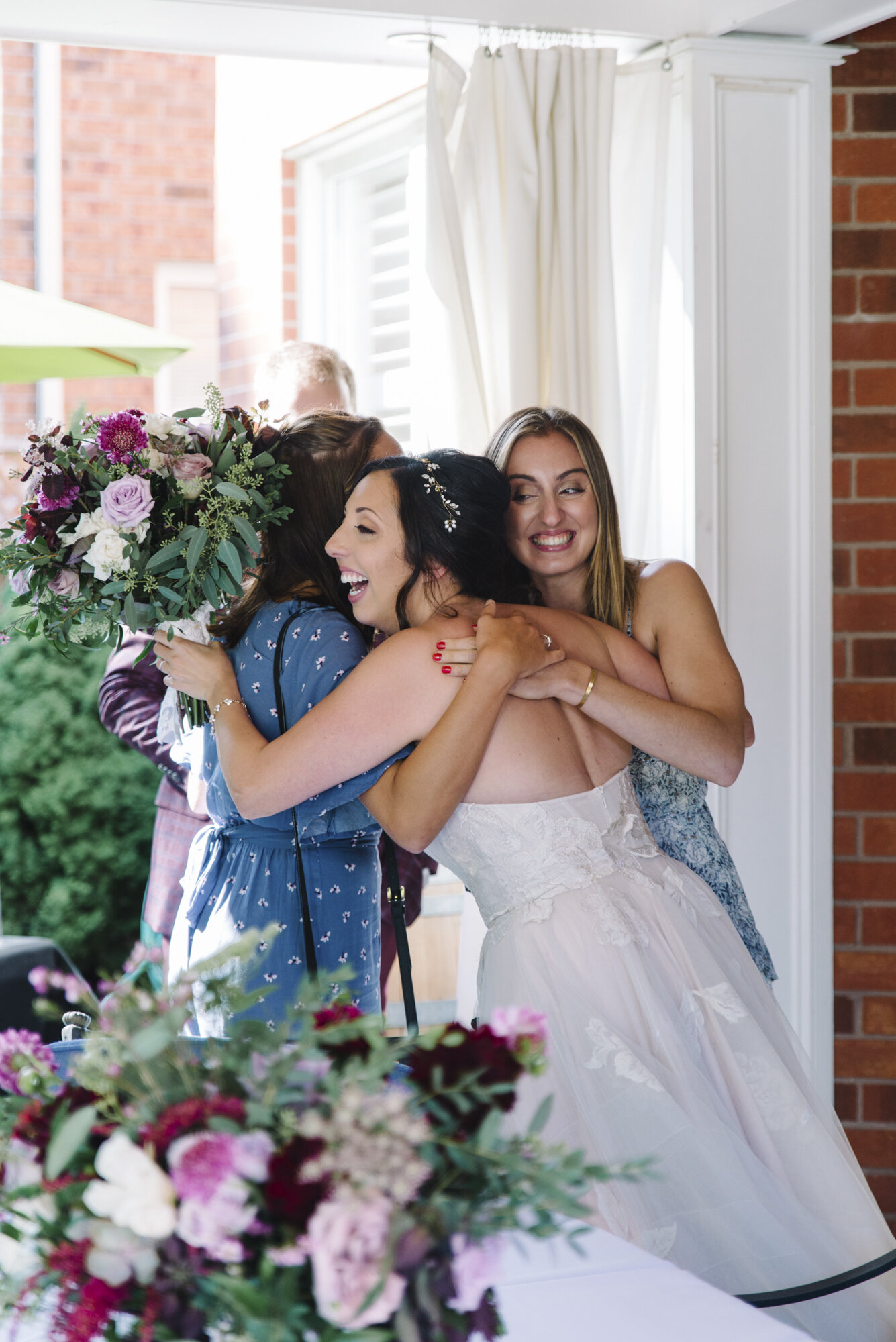 Candid photo of an excited bride hugging guests after her intimate backyard wedding ceremony