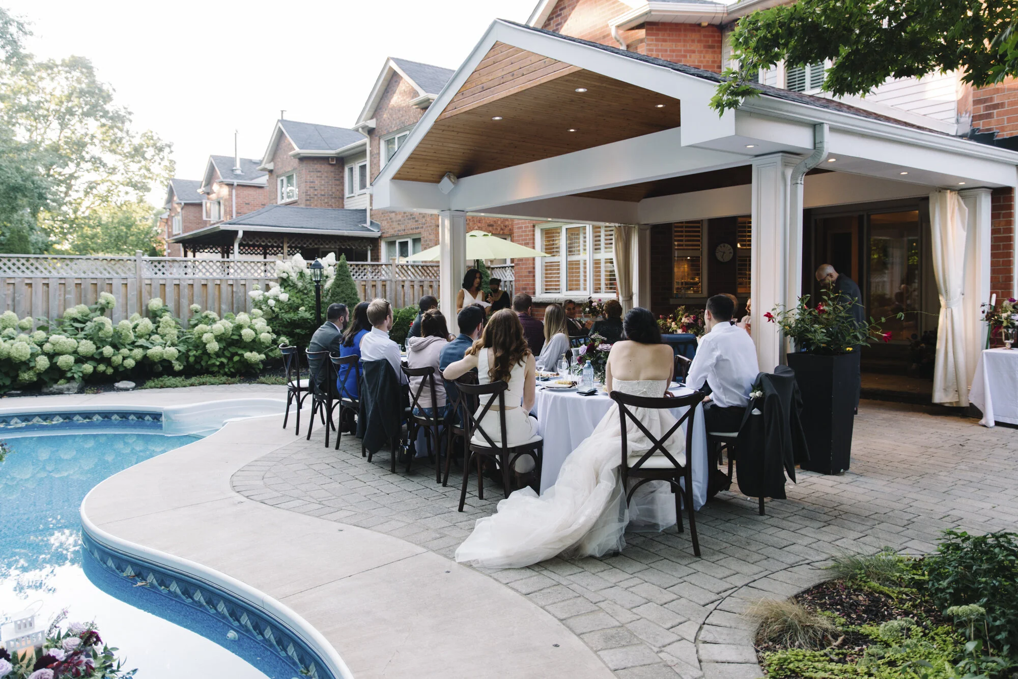 Wide photo of a backyard wedding reception dinner beside the pool at an intimate micro-wedding