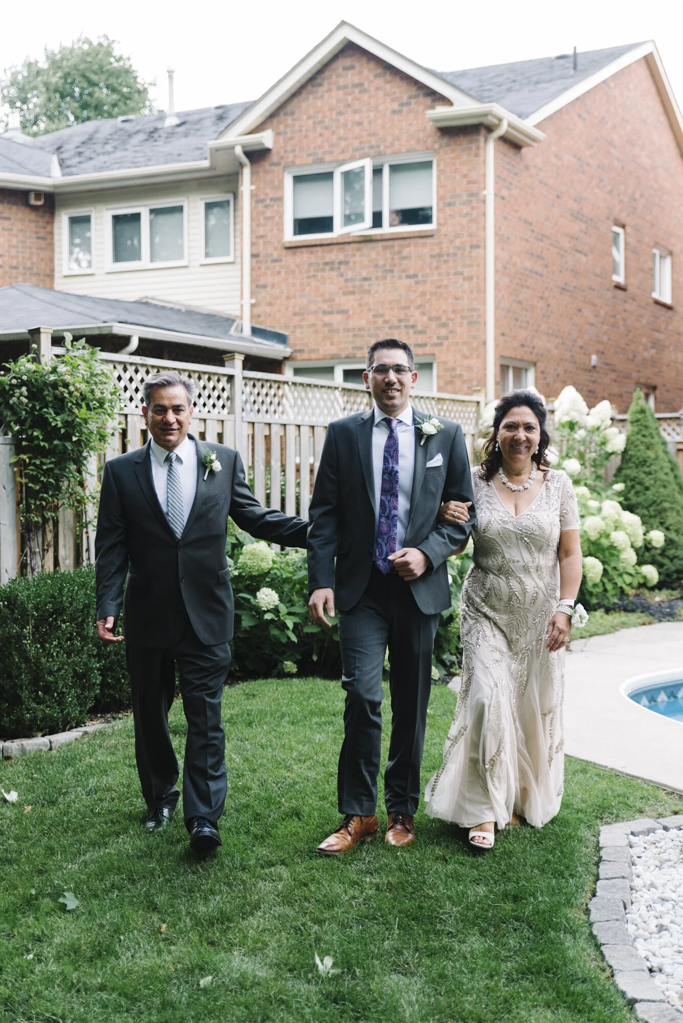 Candid photo of a groom walking with his parents to the ceremony at an intimate backyard wedding in Mississauga