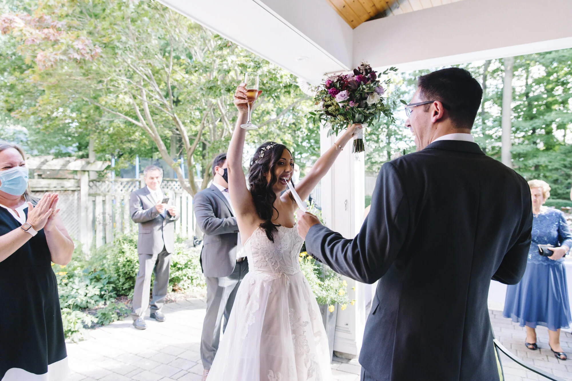 Candid photo of a bride excitedly cheering at her groom after their backyard wedding ceremony in Mississauga