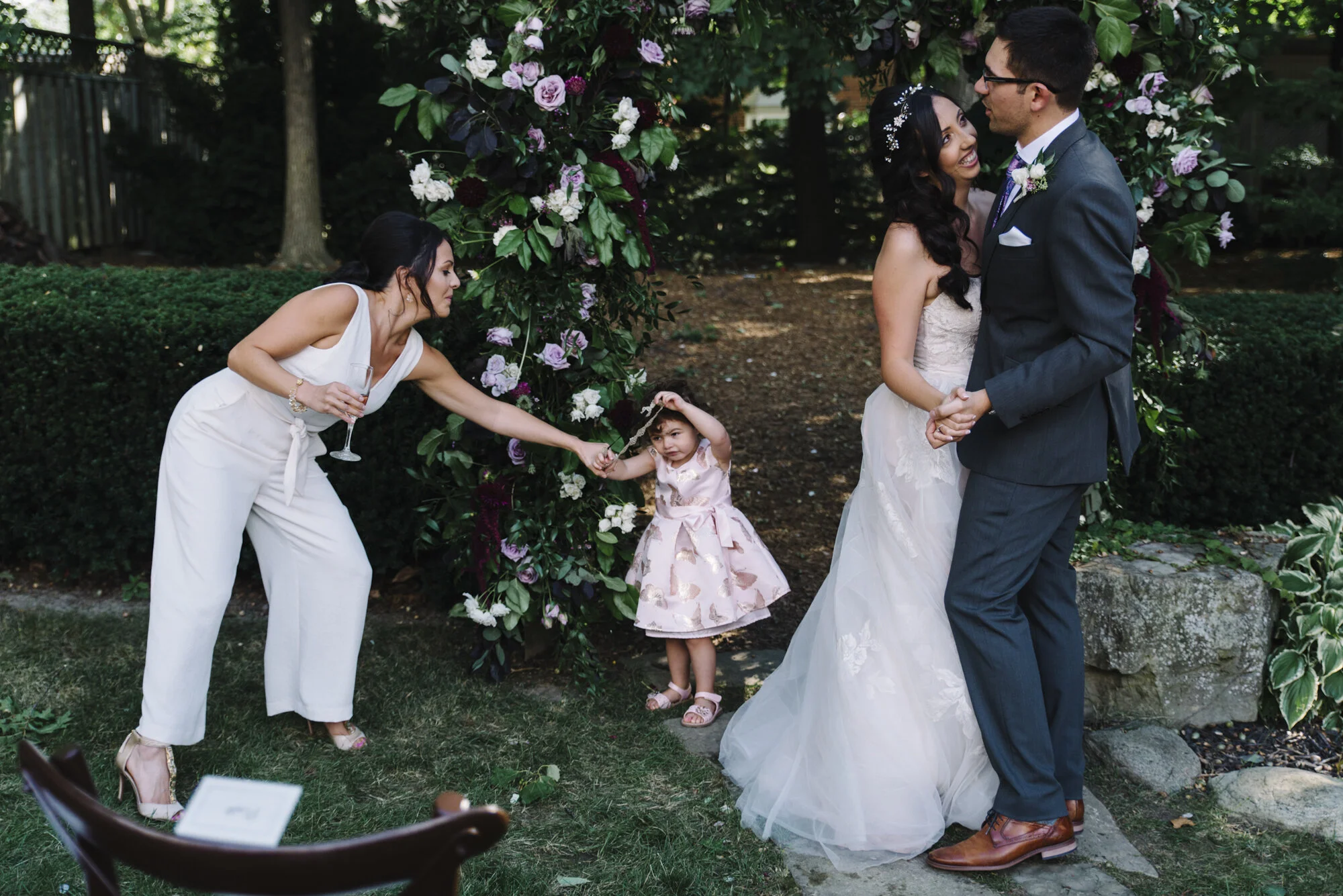 Candid photo of a bride and groom sharing their first dance while a child dances beside them at a backyard wedding reception in Toronto