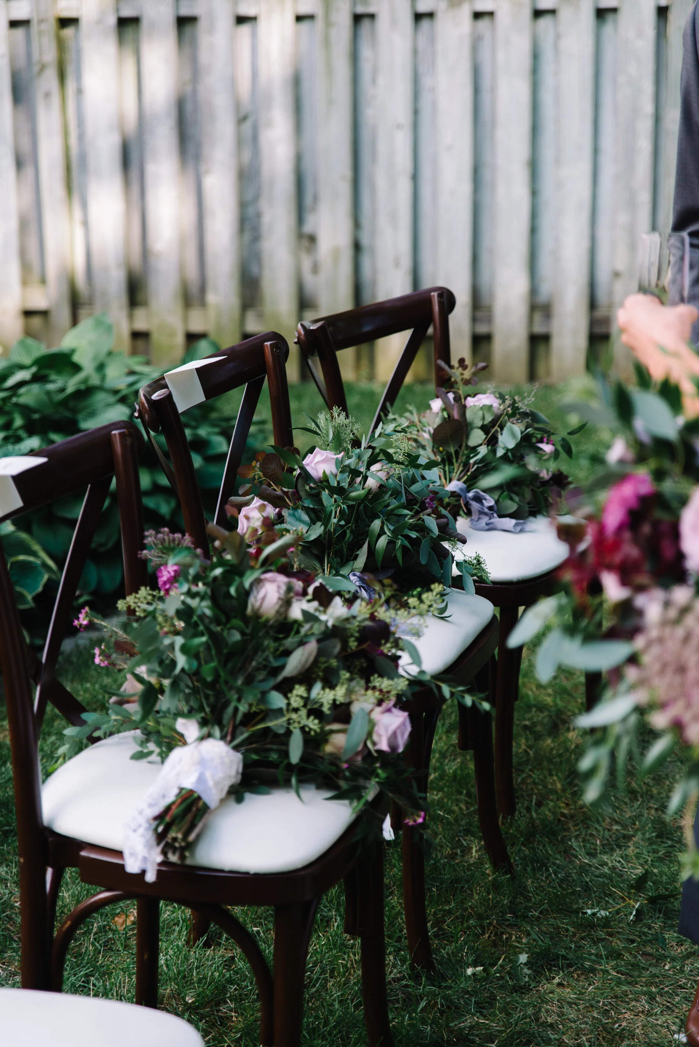 Detail photo of ceremony chairs decorated with bouquets at a backyard micro-wedding in Toronto