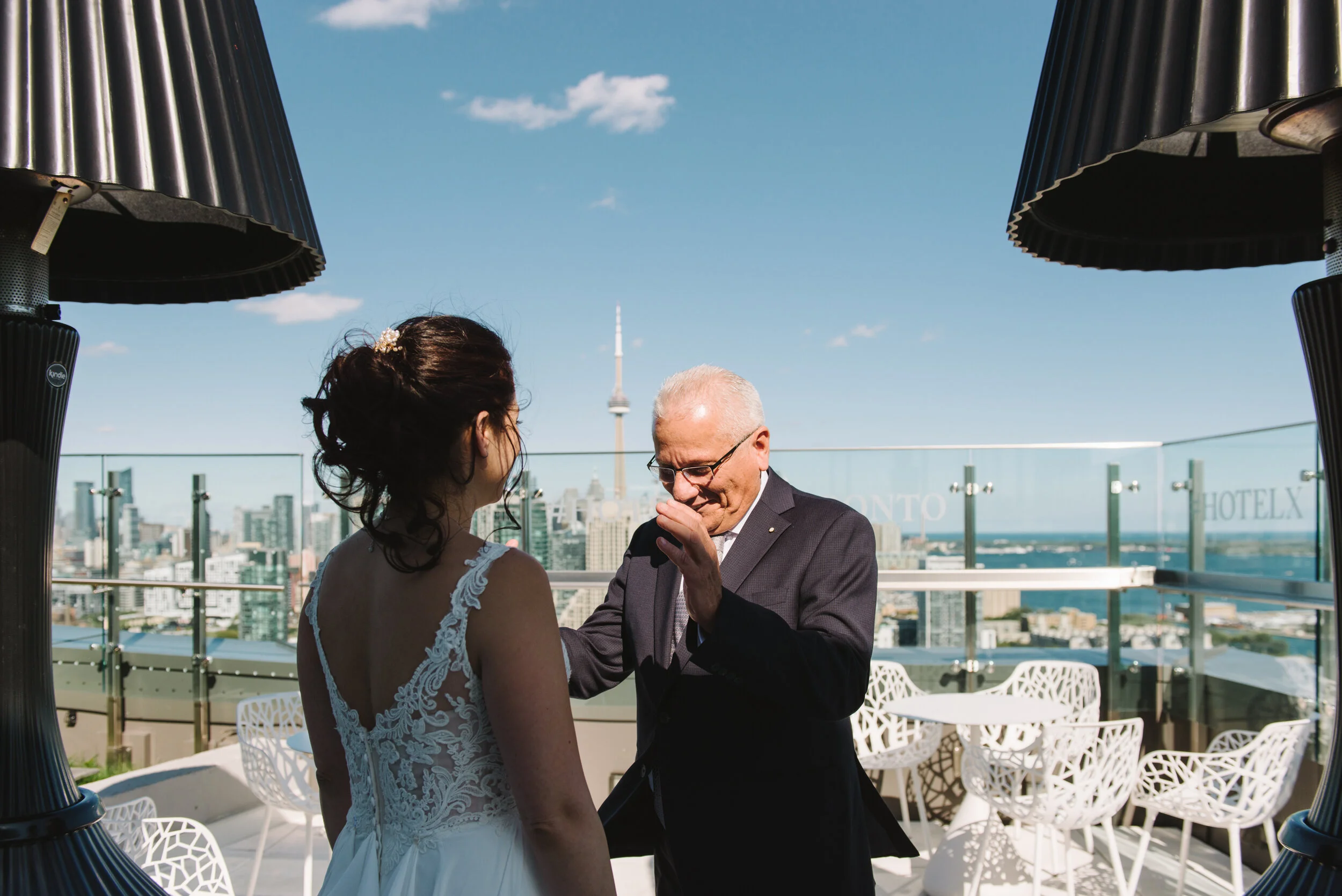 An emotional father-daughter first look on the rooftop of Hotel X in Toronto with the CN Tower visible in the background