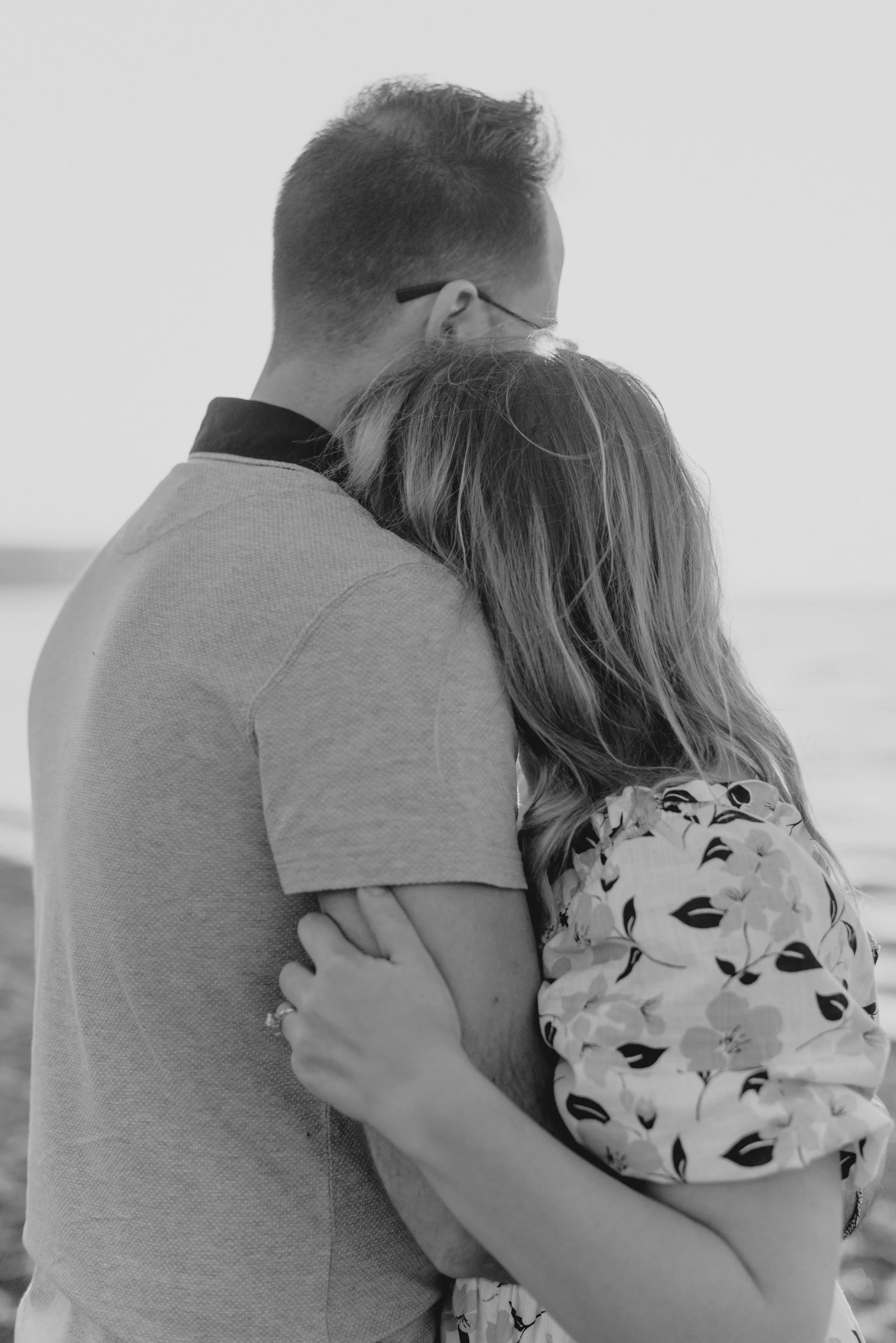 Black and white close up portrait of a couple holding each other during a sunrise engagement session at Woodbine Beach, Toronto
