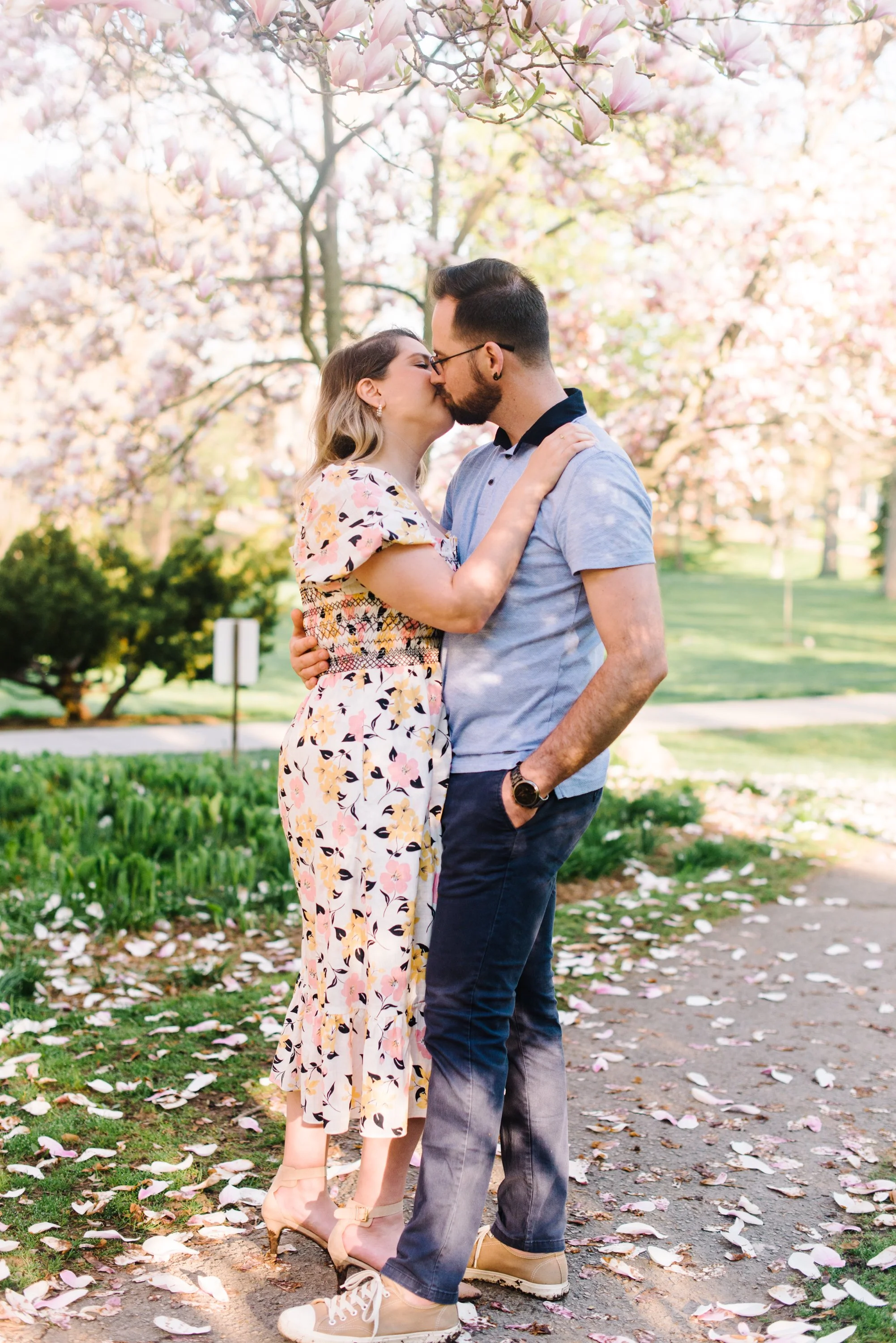 Portrait of a couple sharing a kiss under a magnolia tree during their engagement session at Woodbine Beach, Toronto
