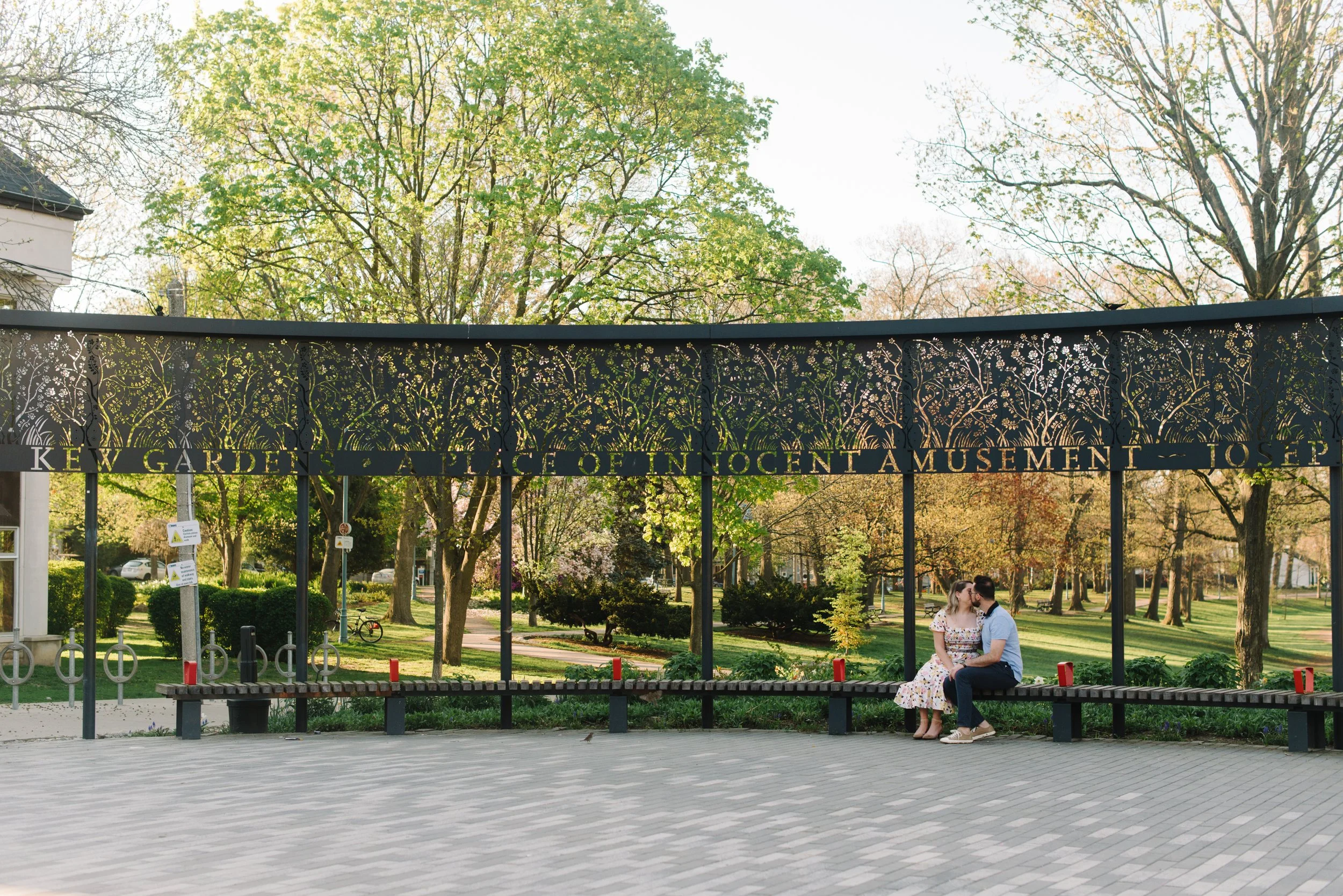 Couple sitting together on benches in Kew Gardens in The Beaches neighbourhood during their sunrise engagement session in Toronto