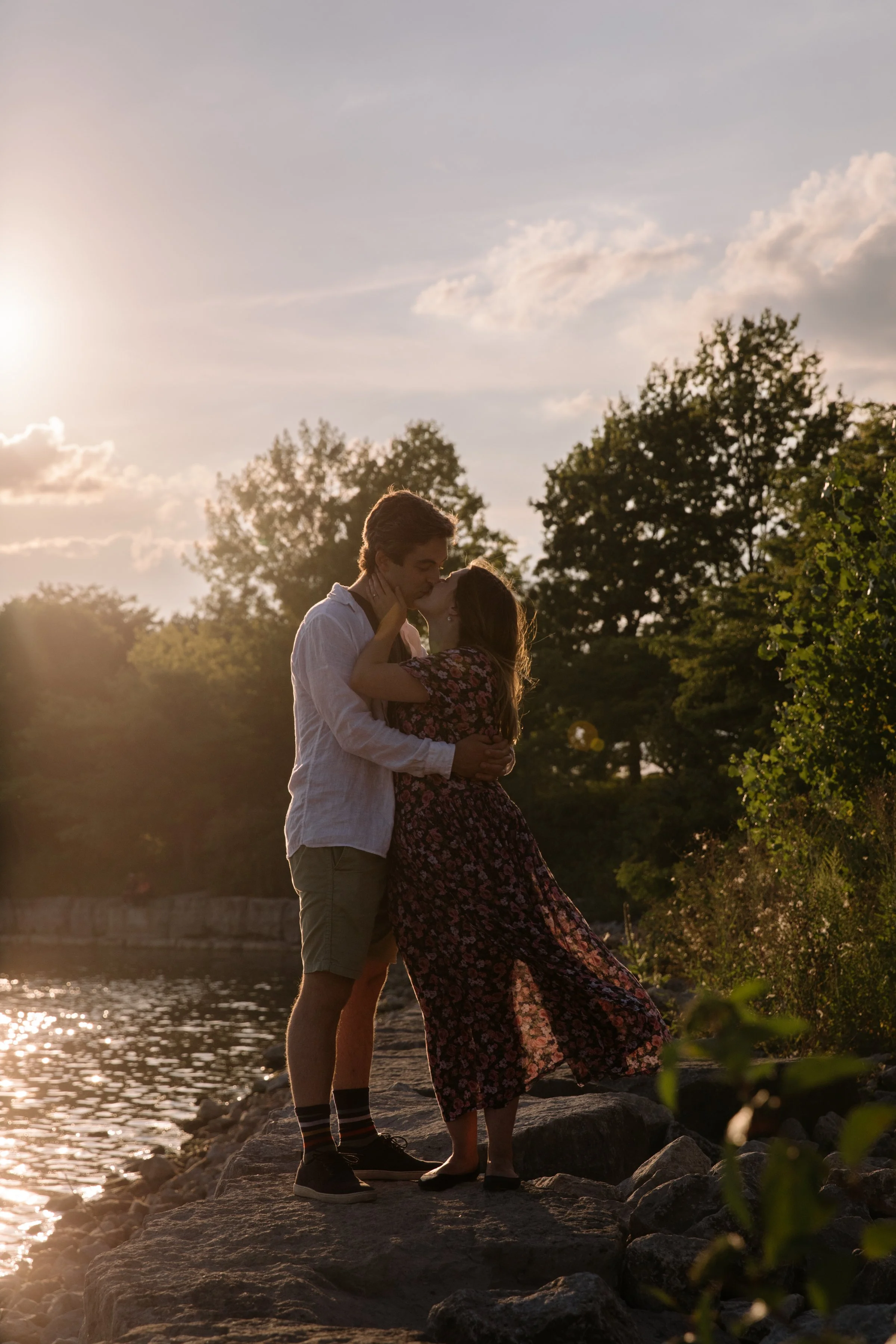 Engaged couple kissing on the rocks at sunset during a waterfront engagement session in Toronto