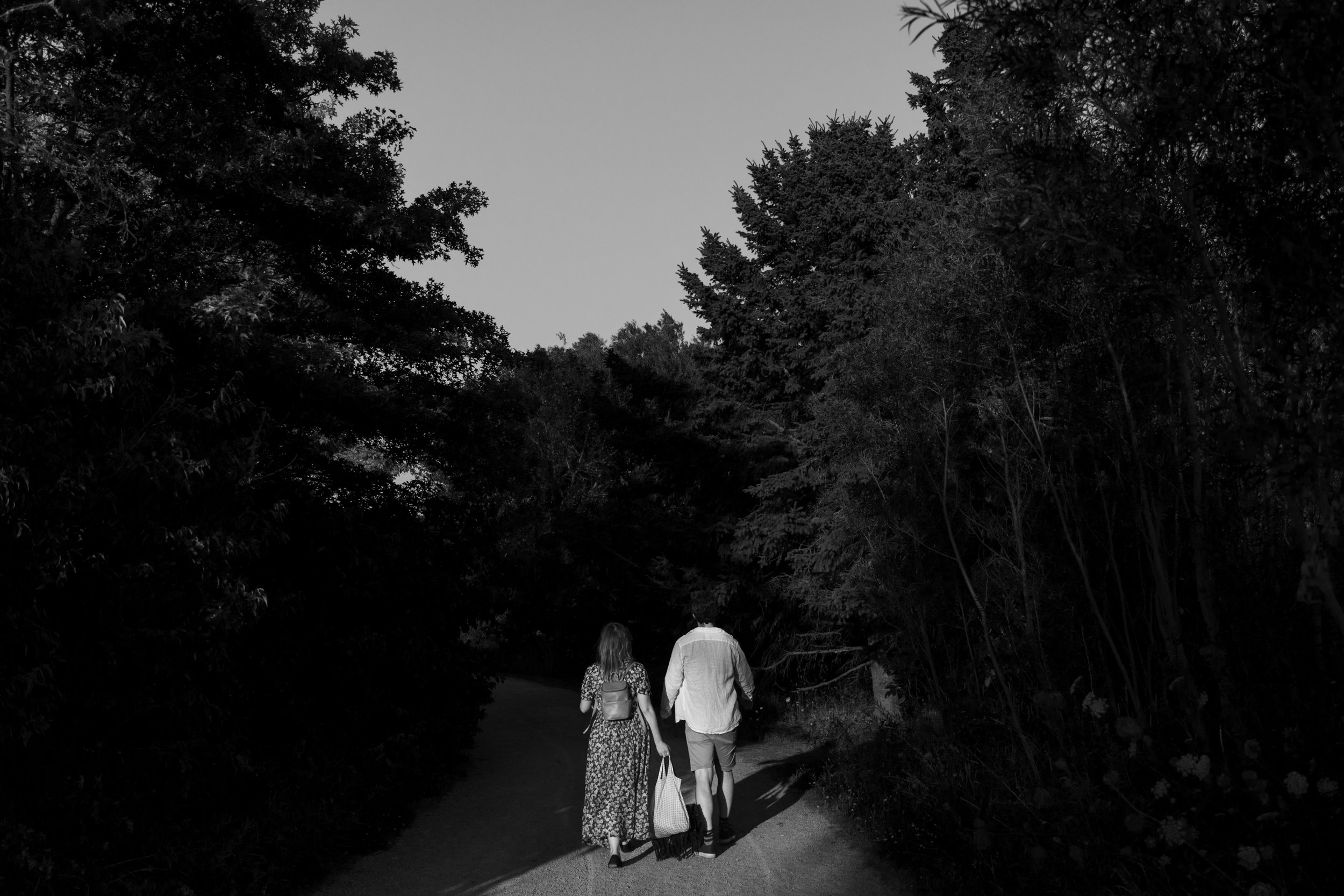 Black and white photo of a couple walking hand in hand on a trail at Colonel Samuel Smith Park