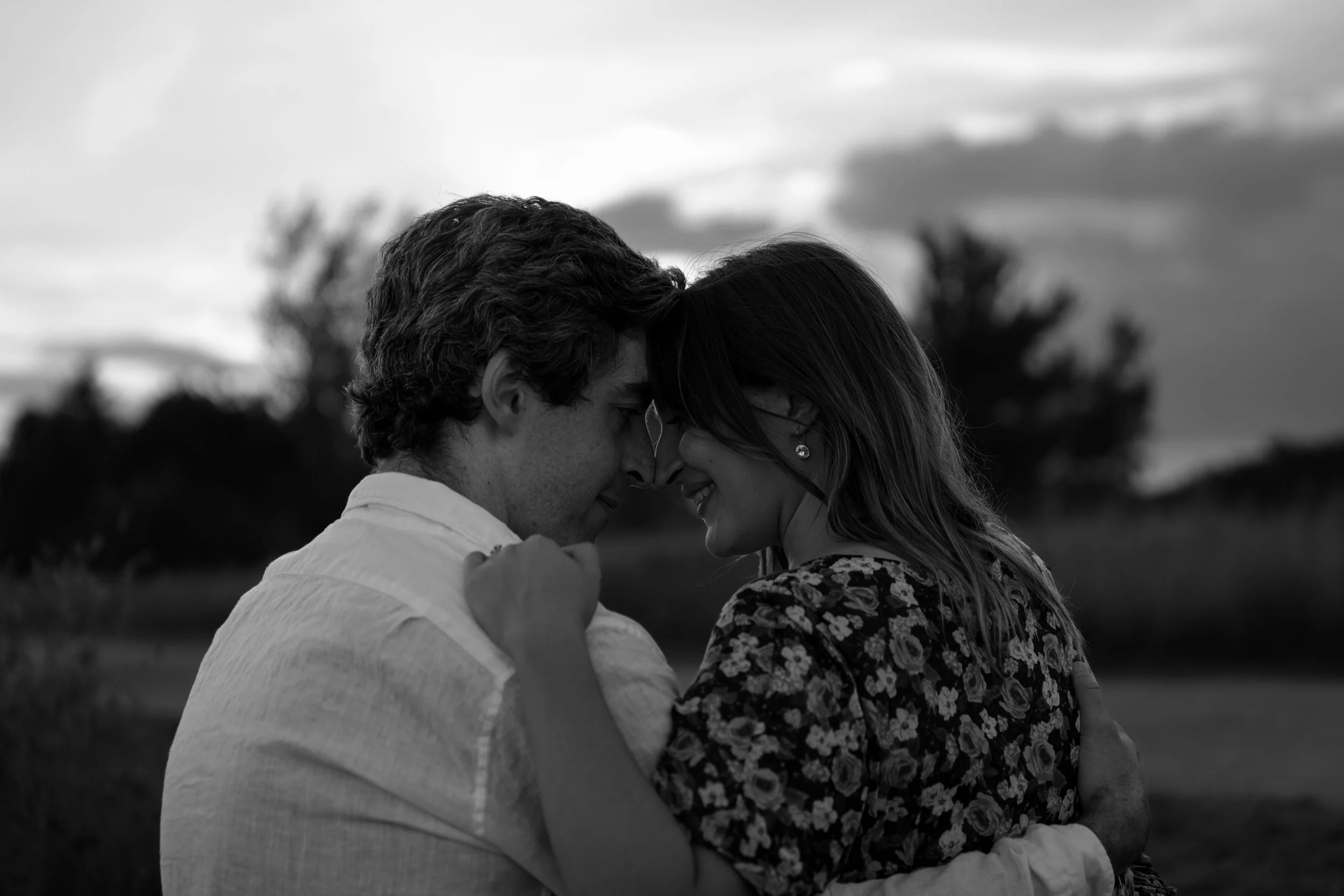 Black and white photo taken from behind of an engaged couple sitting face to face romantically at the Toronto waterfront