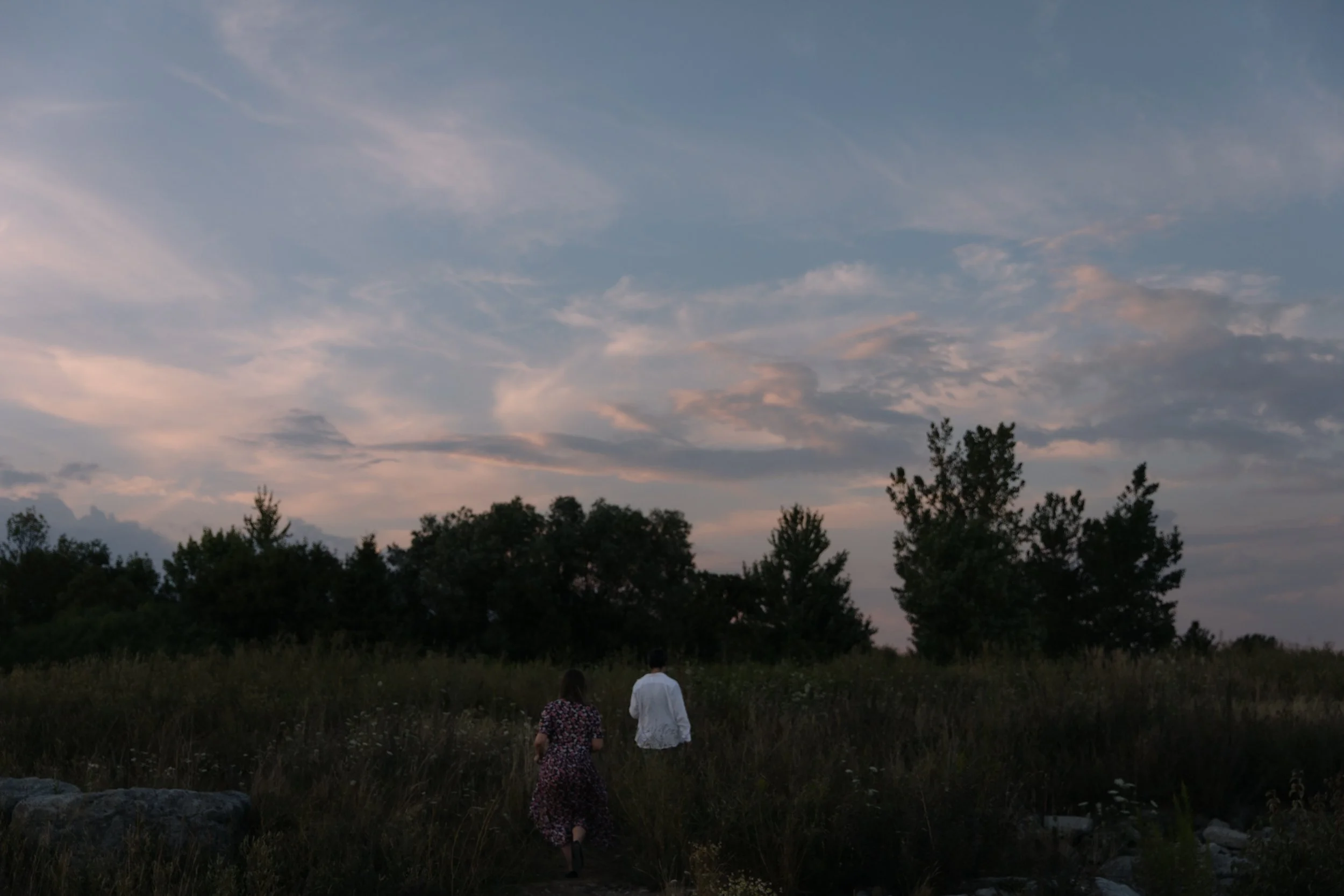 Couple walking into an open field during blue hour after sunset at Colonel Samuel Smith Park, Toronto